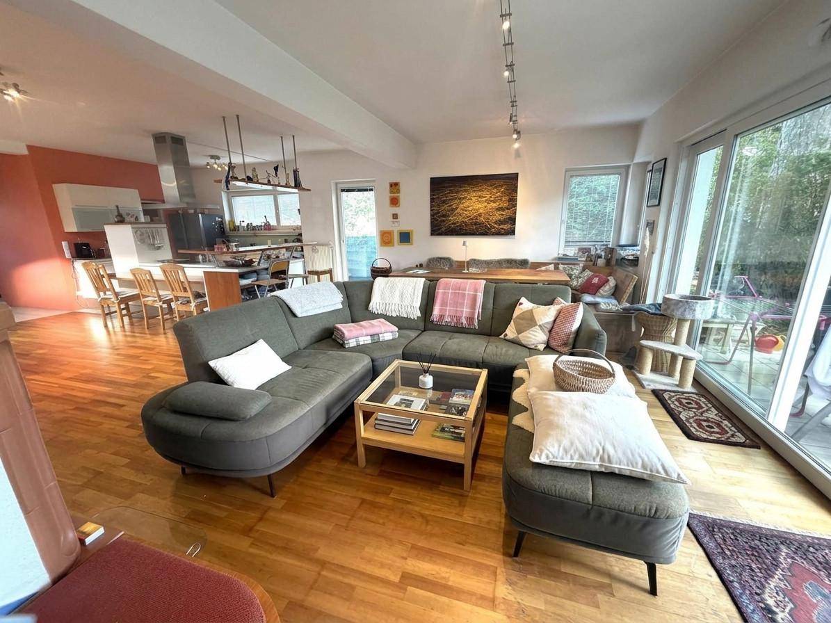 Gemütlicher Wohnbereich mit großem Sofa, Holzboden und Zugang zur Terrasse.