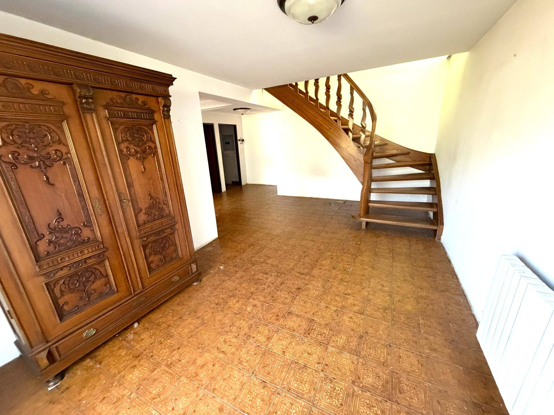 Geräumiger Flur mit Holztreppe und einem großen, verzierten Holzschrank.