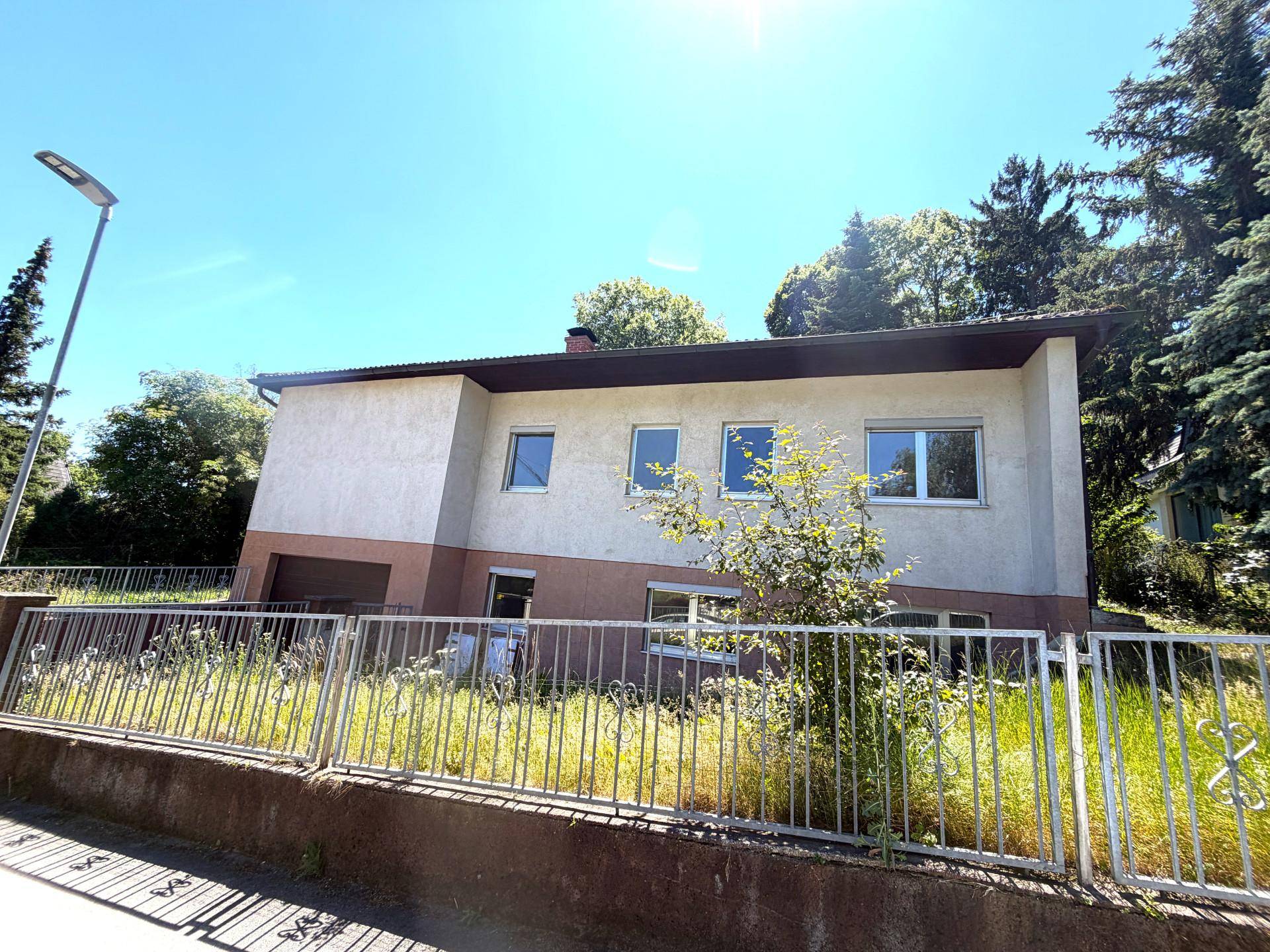 Seitenansicht des Hauses mit einfacher Fassade und umzäuntem Vorgartenbereich.