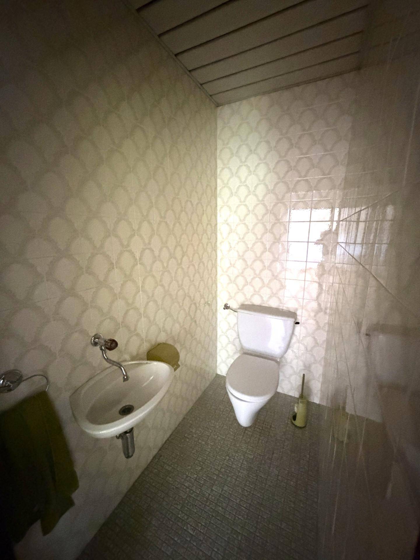 Kleines Gäste-WC mit Wand-WC, Waschbecken und gemusterten Fliesen an den Wänden.