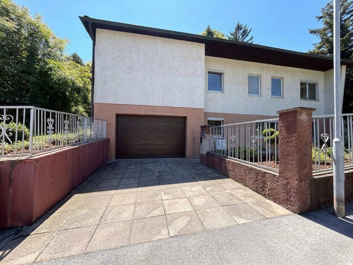 Vorderansicht des Hauses mit integrierter Garage und gepflasterter Auffahrt.