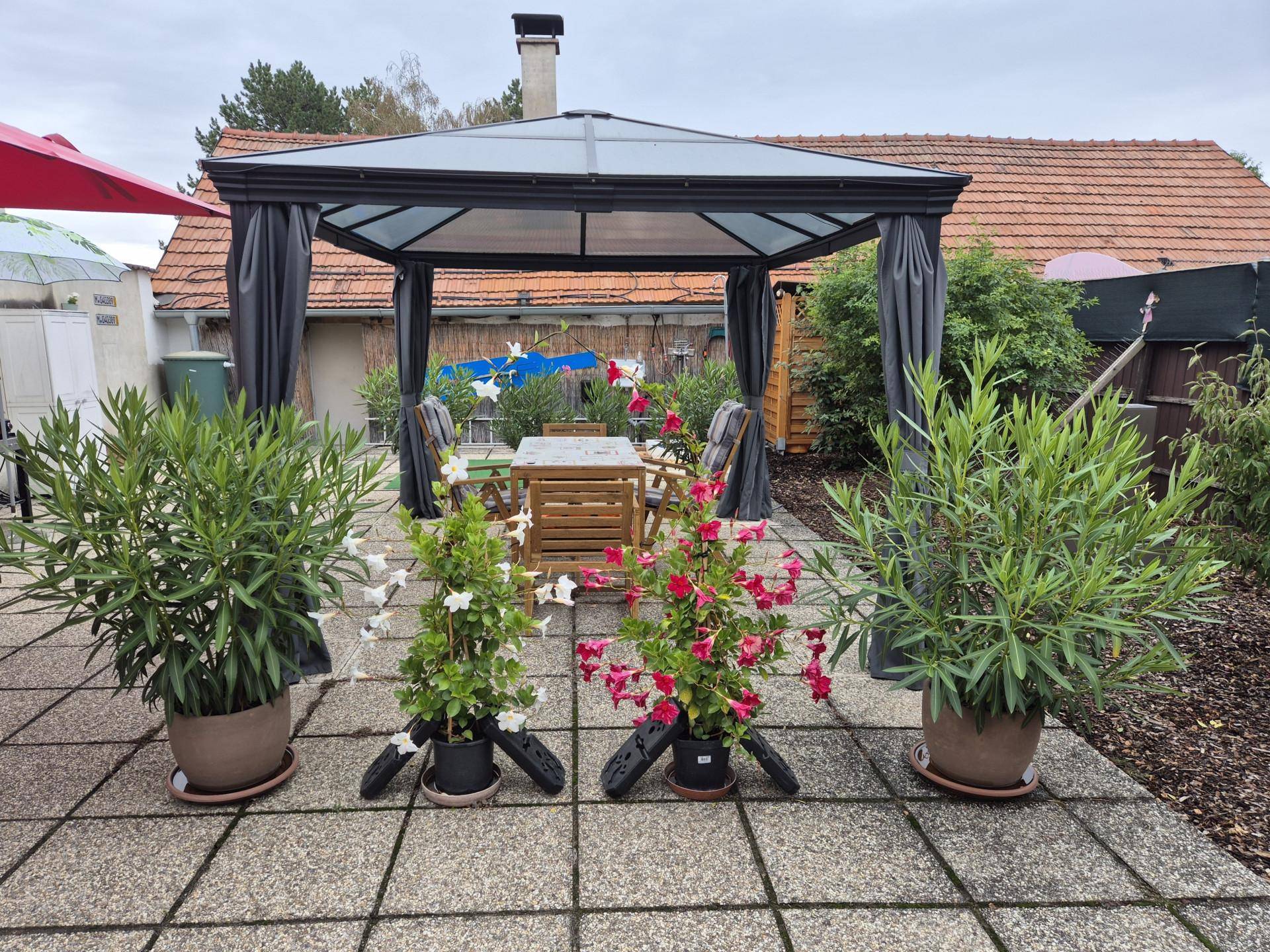 Große gepflasterte Terrasse mit einem Pavillon und Gartenmöbeln für entspannte Stunden.