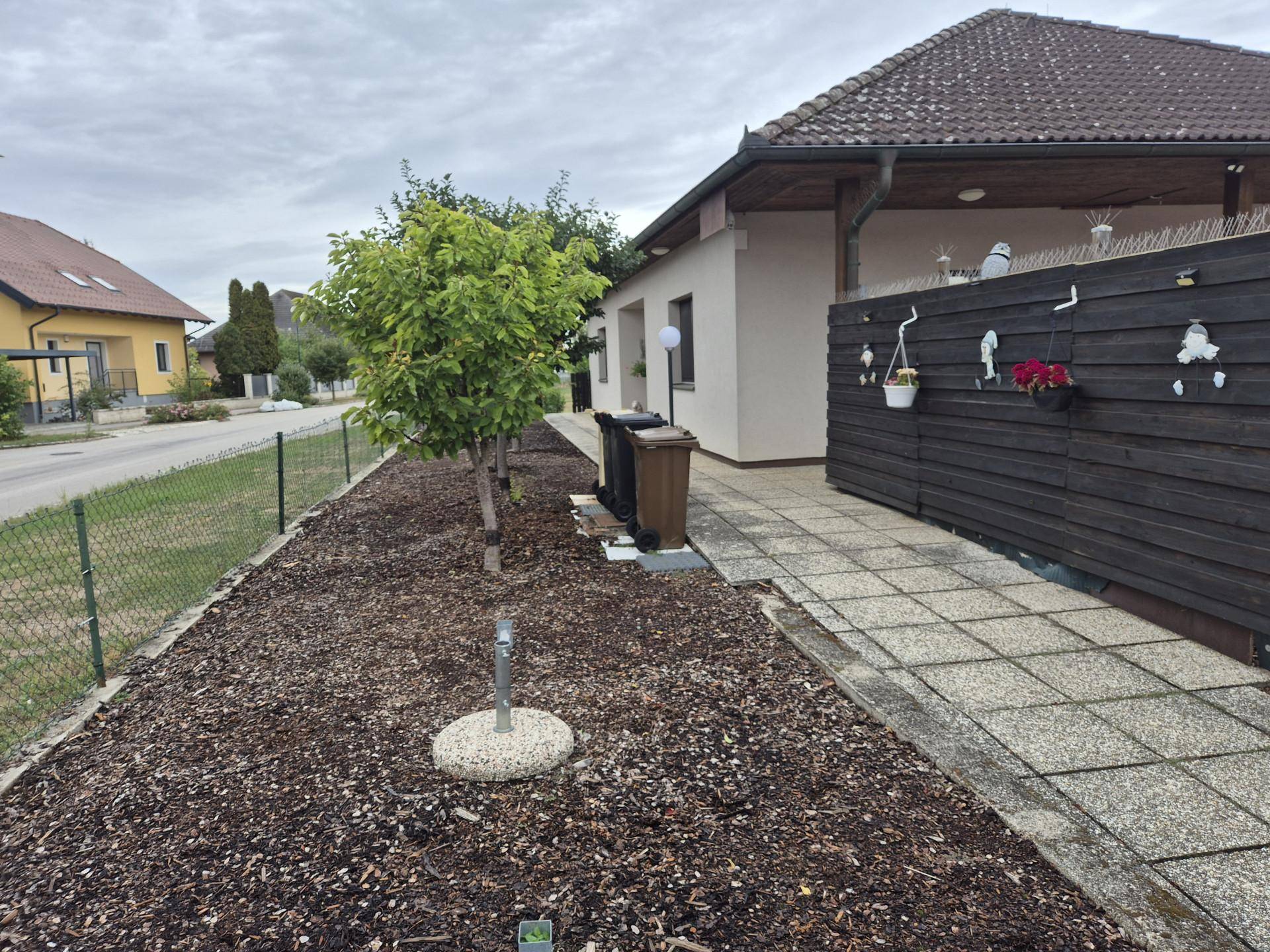 Seitenansicht des Hauses mit gepflastertem Weg und bepflanztem Bereich.