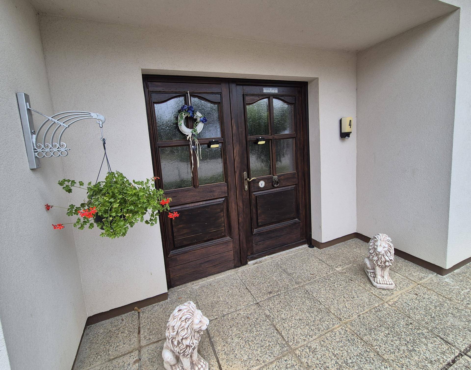 Eingangsbereich des Hauses mit doppelter Holztür und dekorativen Löwenstatuen.