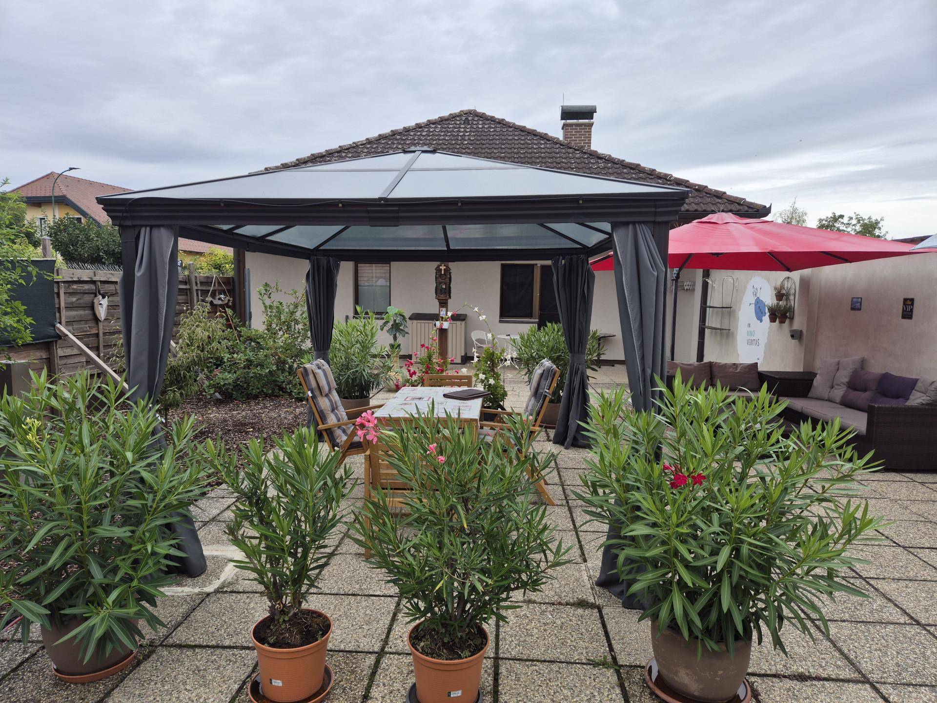 Große gepflasterte Terrasse mit einem Pavillon und Gartenmöbeln für entspannte Stunden.