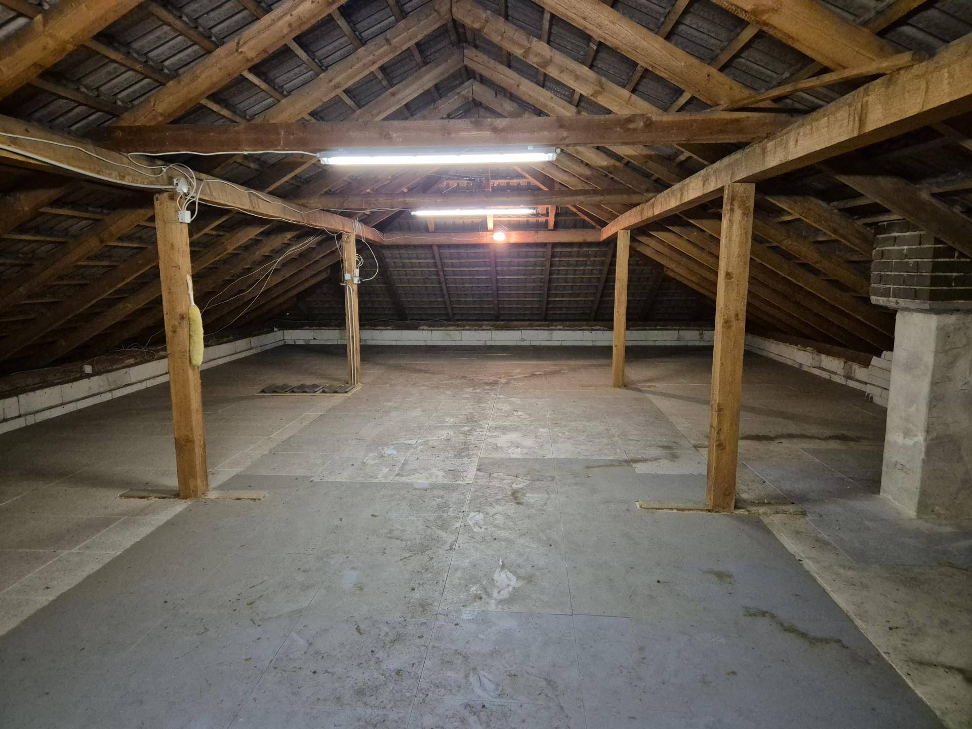 Geräumiger Dachboden mit sichtbaren Holzbalken und viel Stauraum.