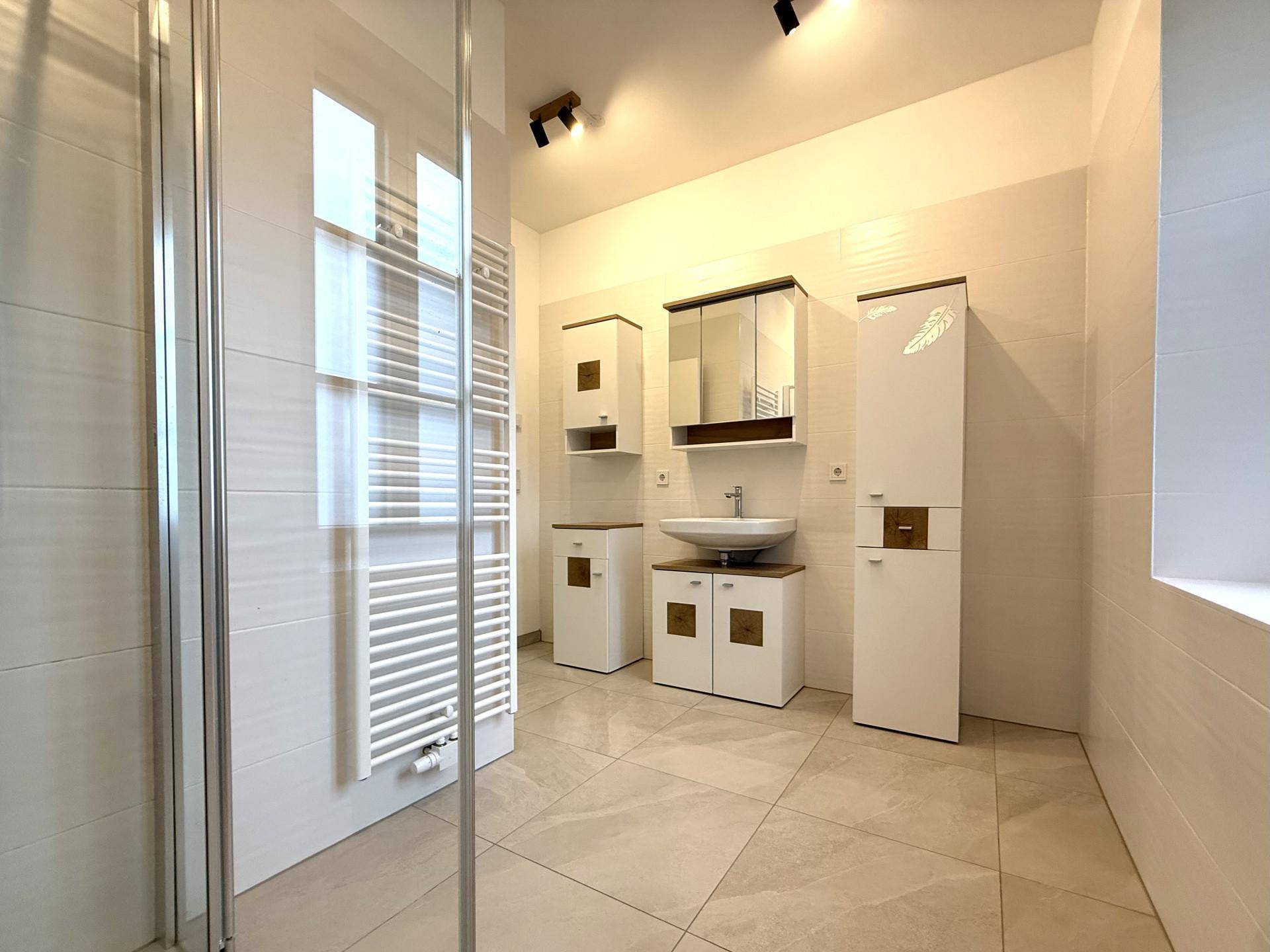 Modernes Badezimmer mit begehbarer Dusche, Handtuchheizkörper und eleganten Fliesen.
