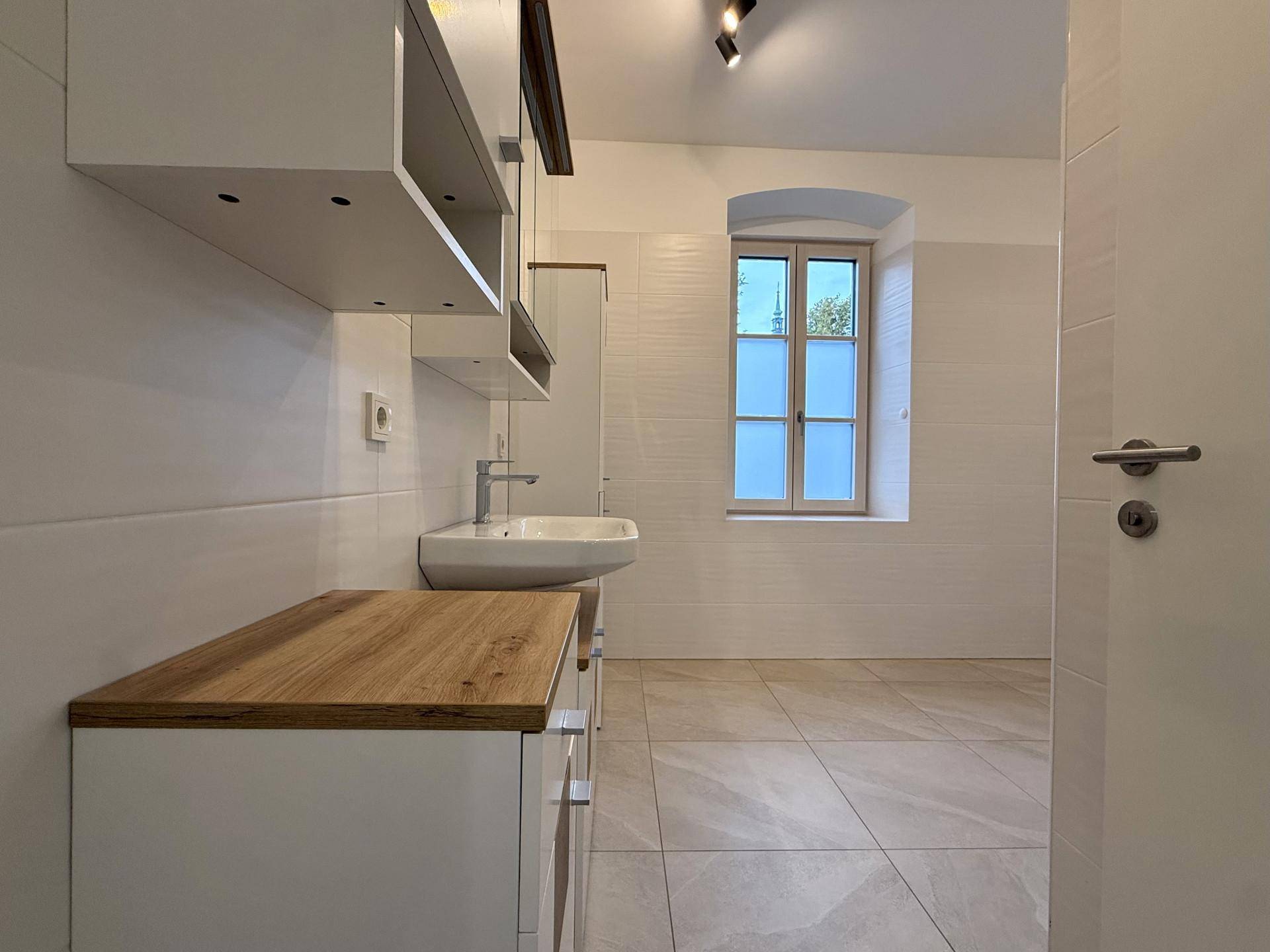 Modernes Badezimmer mit Waschtisch, Spiegelschrank und Fenster für natürliches Licht.