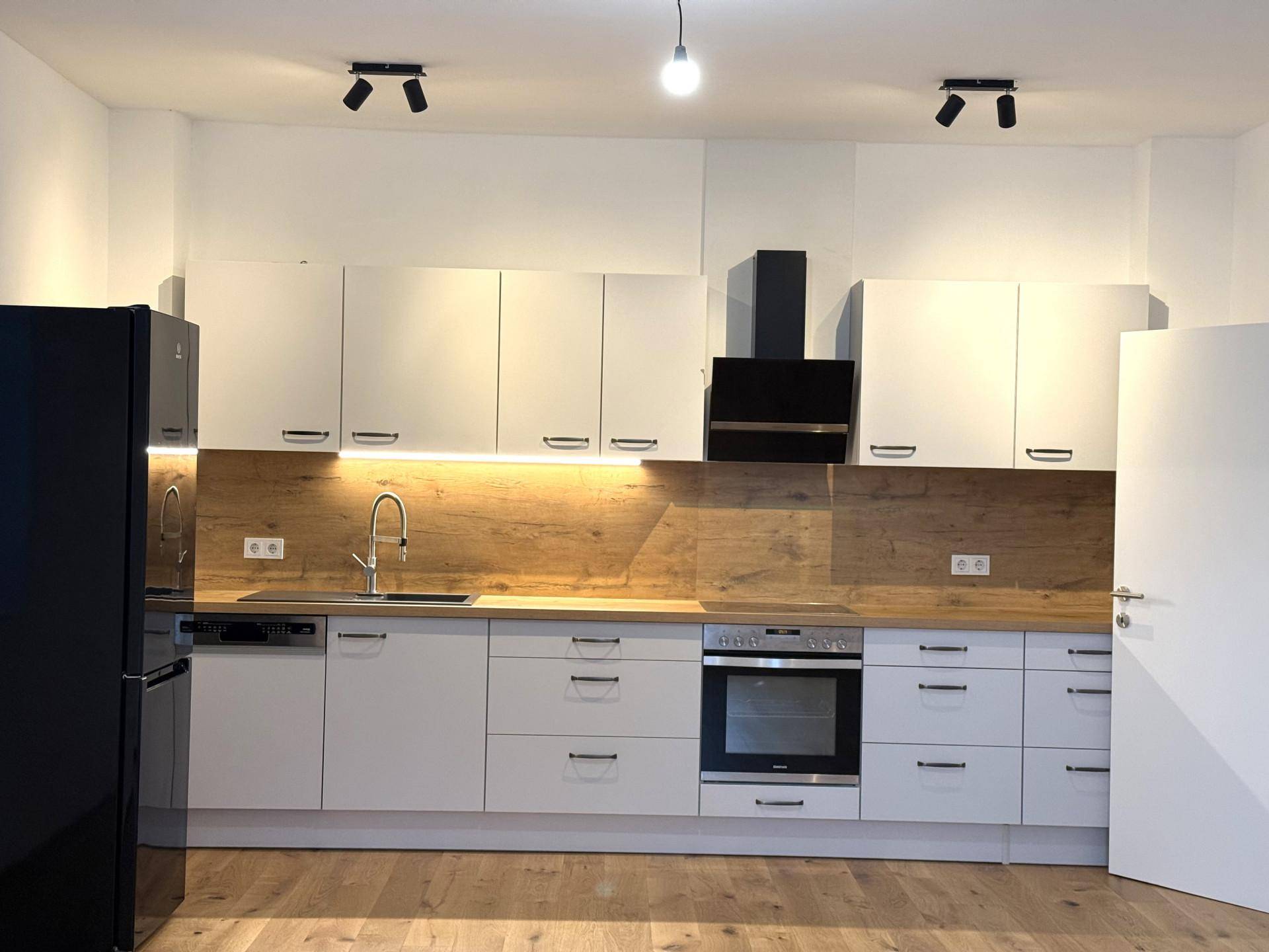 Moderne Einbauküche mit weißen Schränken, Holzoptik-Arbeitsplatte und integrierten Geräten.
