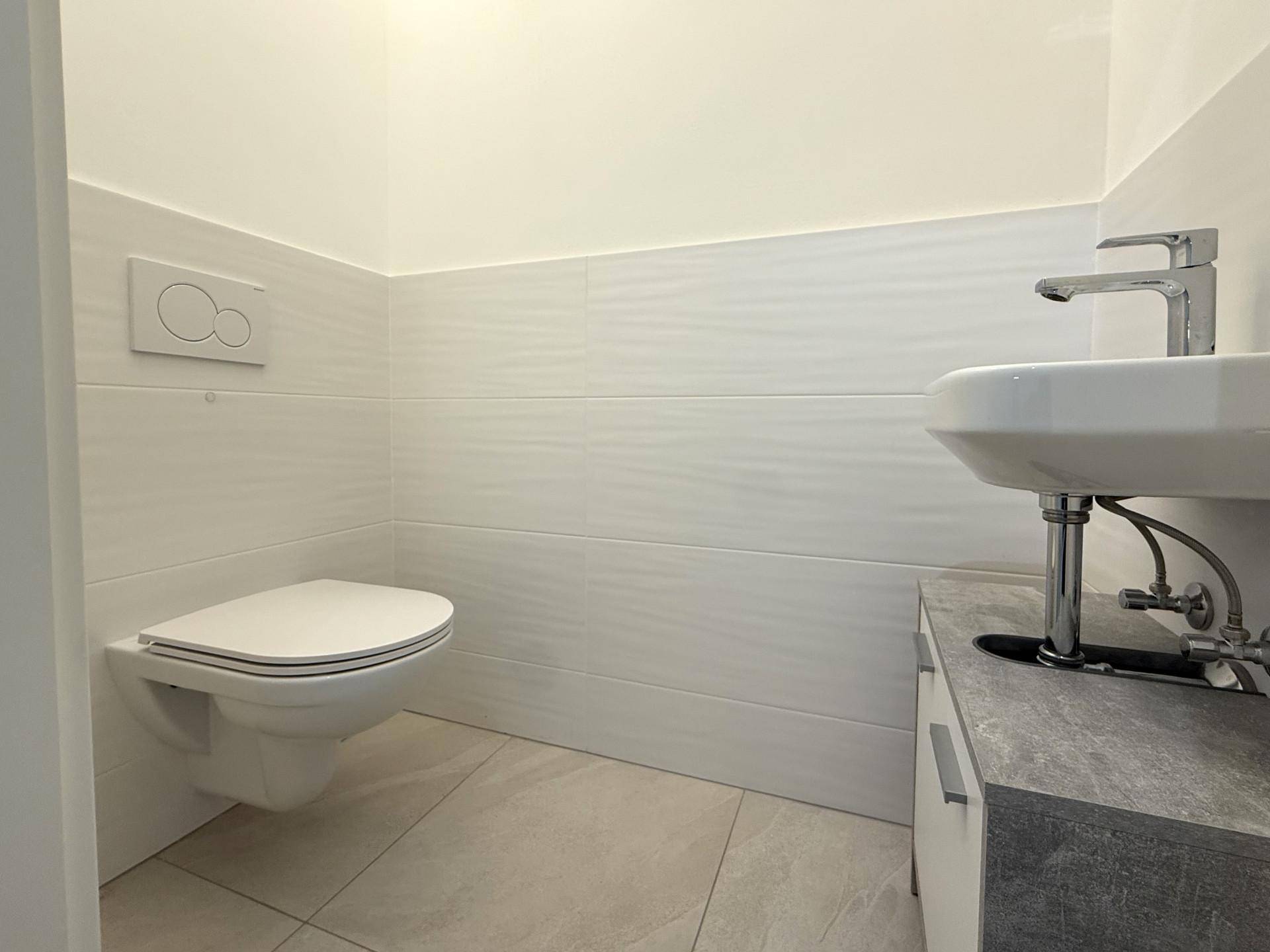 Separate Gästetoilette mit wandhängendem WC und kleinem Waschbecken.