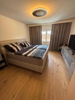 Modernes Schlafzimmer mit Doppelbett, Holzboden und dezenter Deckenbeleuchtung.