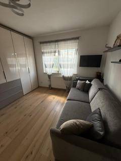 Helles Zimmer mit Schlafsofa, großem Kleiderschrank und Holzboden.