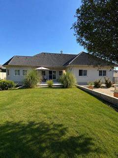 Gepflegter Garten mit weitläufiger Rasenfläche und Terrasse hinter dem Einfamilienhaus.