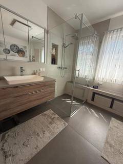 Modernes Badezimmer mit ebenerdiger Dusche, Holzwaschtisch und großem Spiegelschrank.