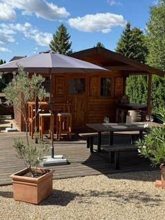 Gemütliches Gartenhaus aus Holz mit Bar, Sitzbereich und Sonnenschirm.