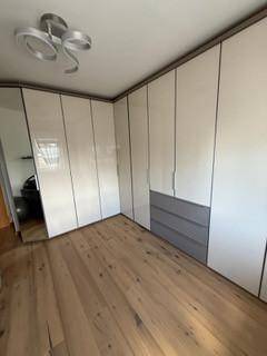 Geräumiges Zimmer mit großem, modernem Einbauschrank und Holzboden.