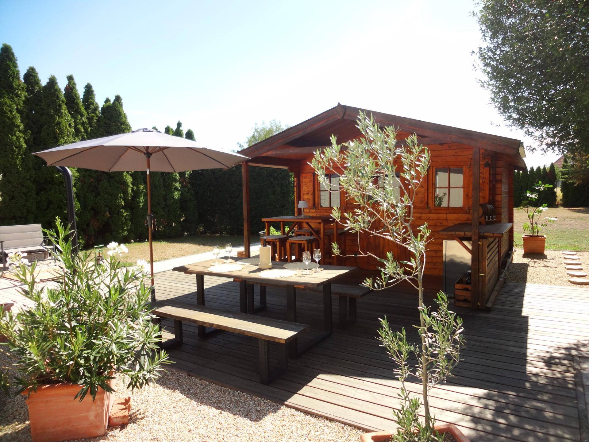 Idyllischer Gartenbereich mit Holzhütte, Esstisch im Freien und mediterranen Pflanzen.
