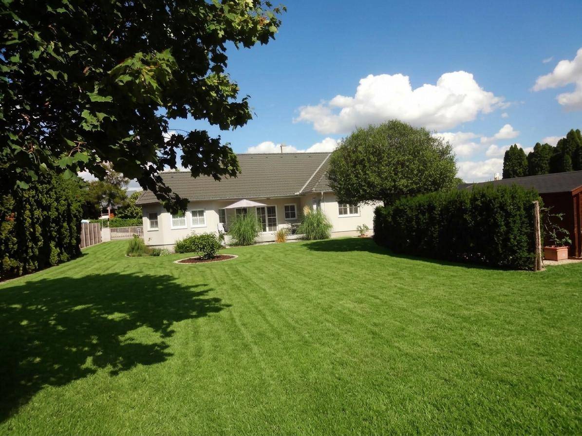 Weitläufiger, gepflegter Garten mit großem Rasen und Blick auf die Rückseite des Hauses.