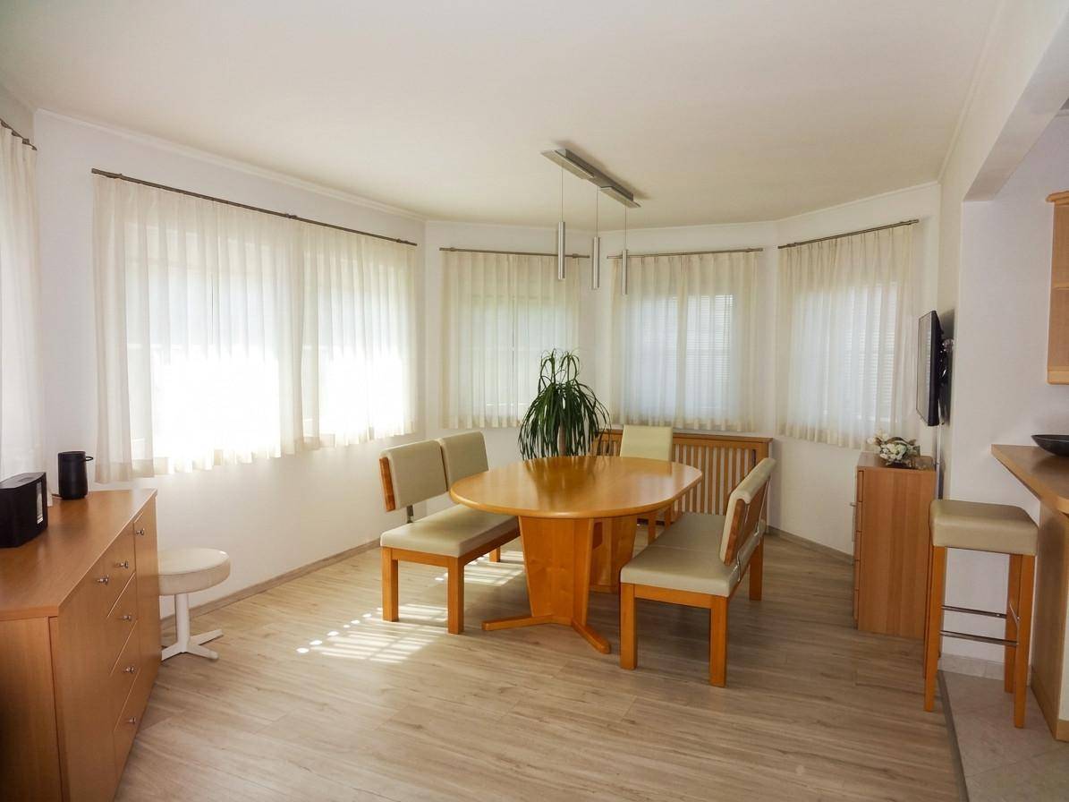 Heller Essbereich mit Holztisch, Stühlen und großen Fenstern für viel Tageslicht.