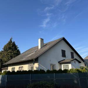Traditionelles Haus mit Satteldach und weißer Fassade unter klarem blauem Himmel.
