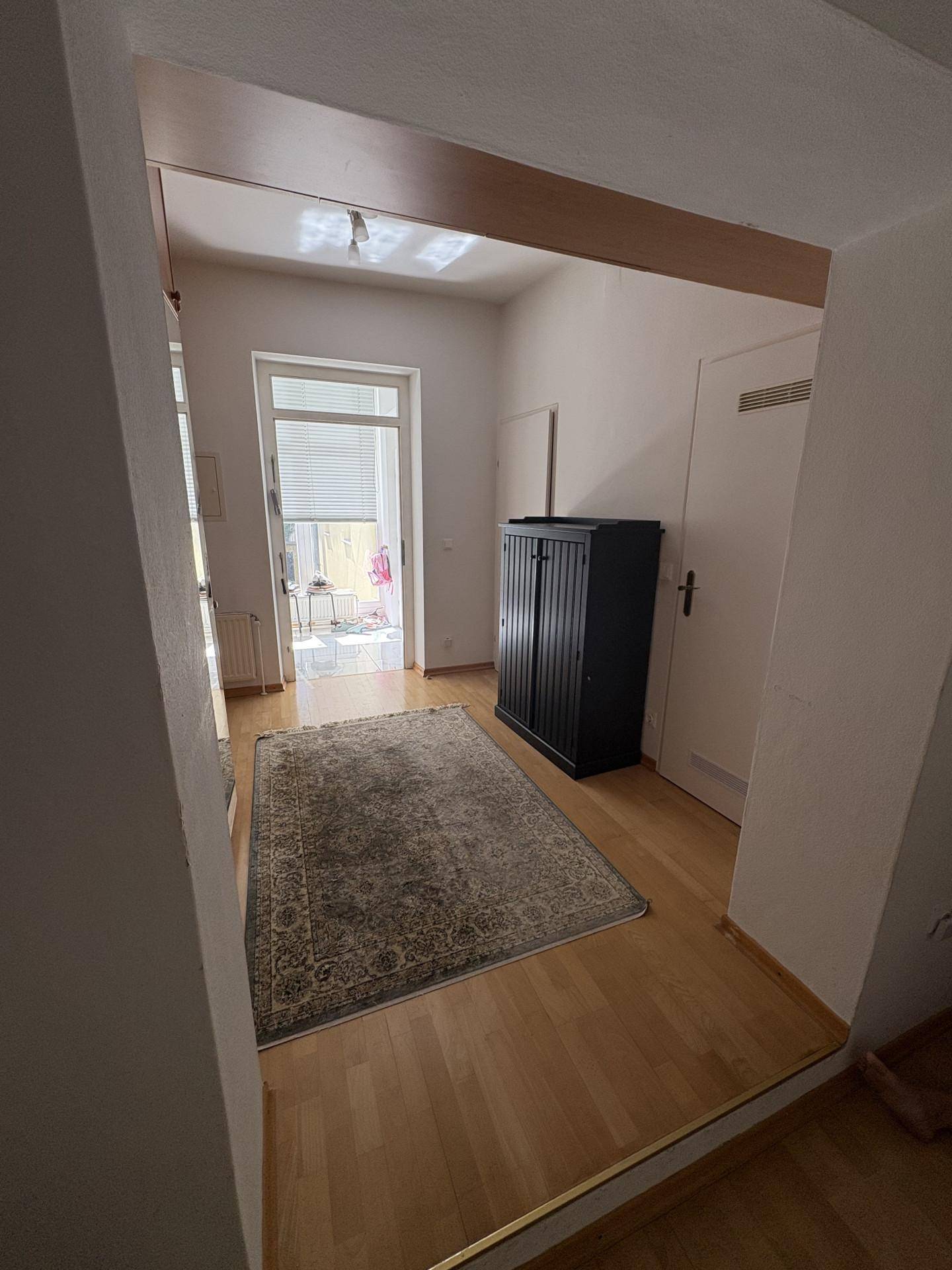 Heller Eingangsbereich mit Holzfußboden, Teppich und Zugang zu einem weiteren Raum.