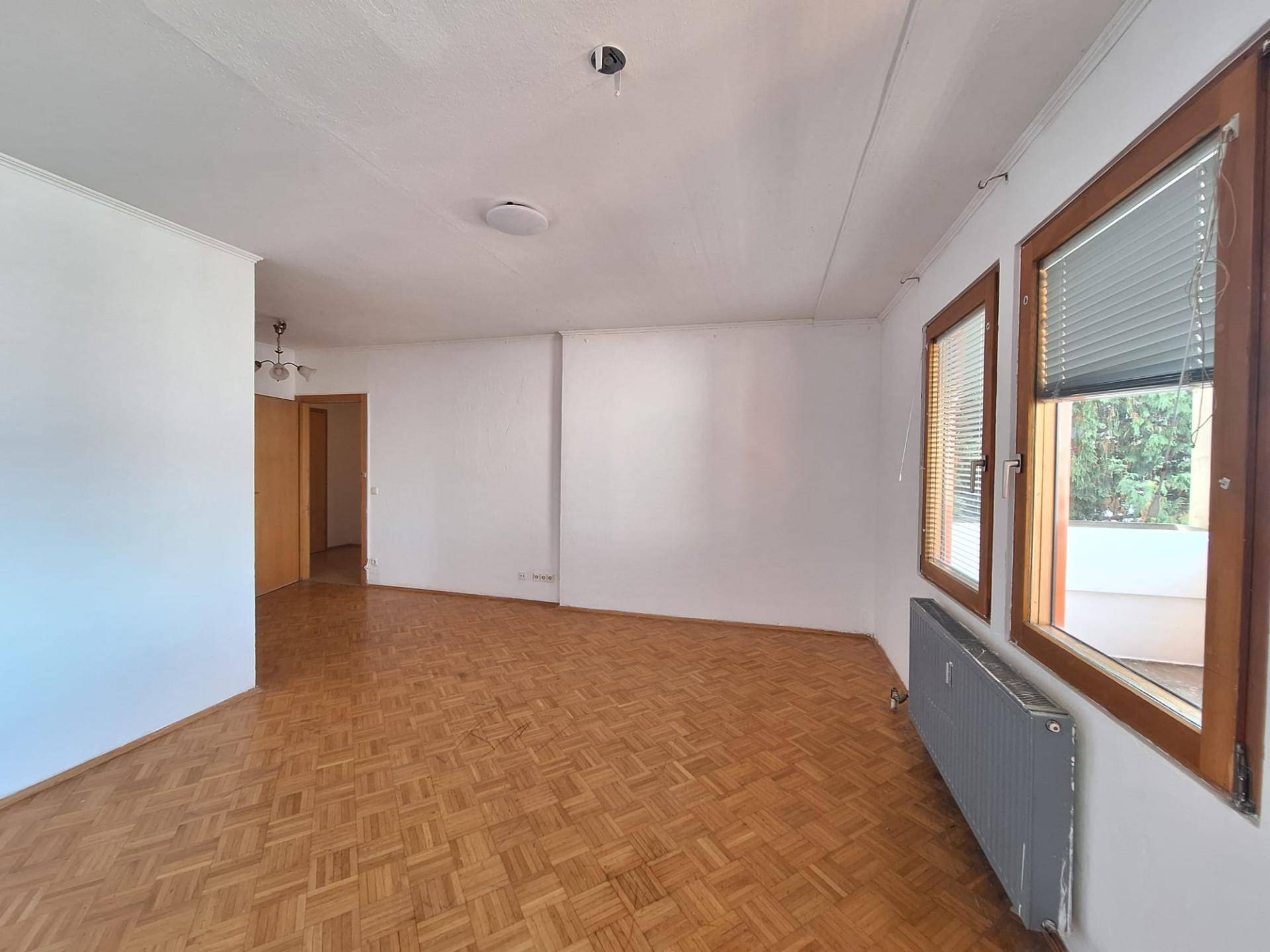 Helles Wohnzimmer mit Fischgrätparkettboden und großen Fenstern, bereit zur individuellen Gestaltung.