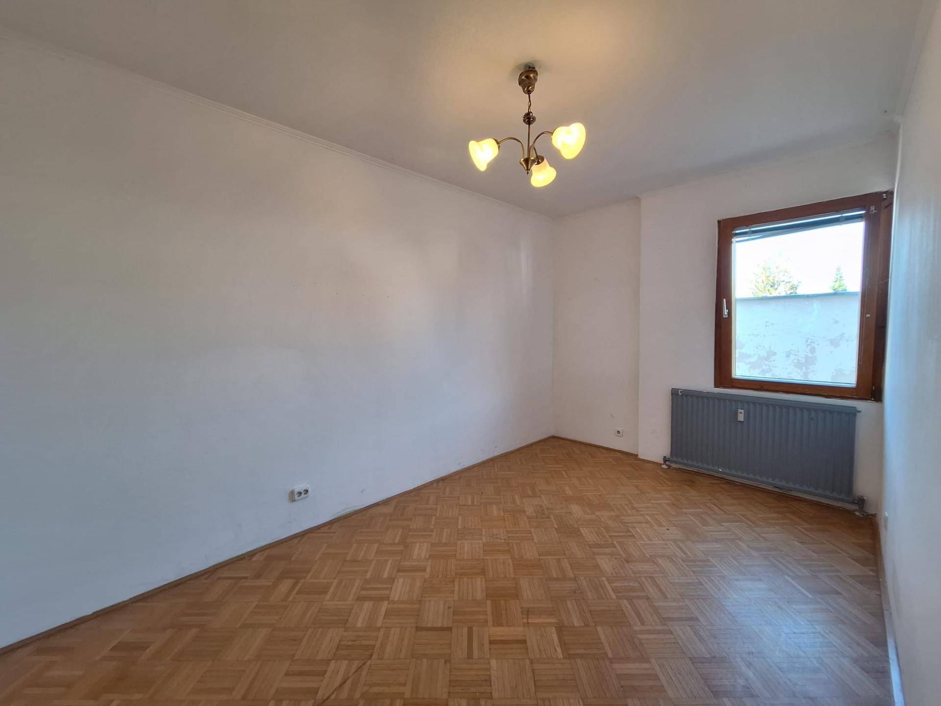 Ruhiges Zimmer mit Parkettboden und einem Fenster, ideal als Schlaf- oder Arbeitszimmer.
