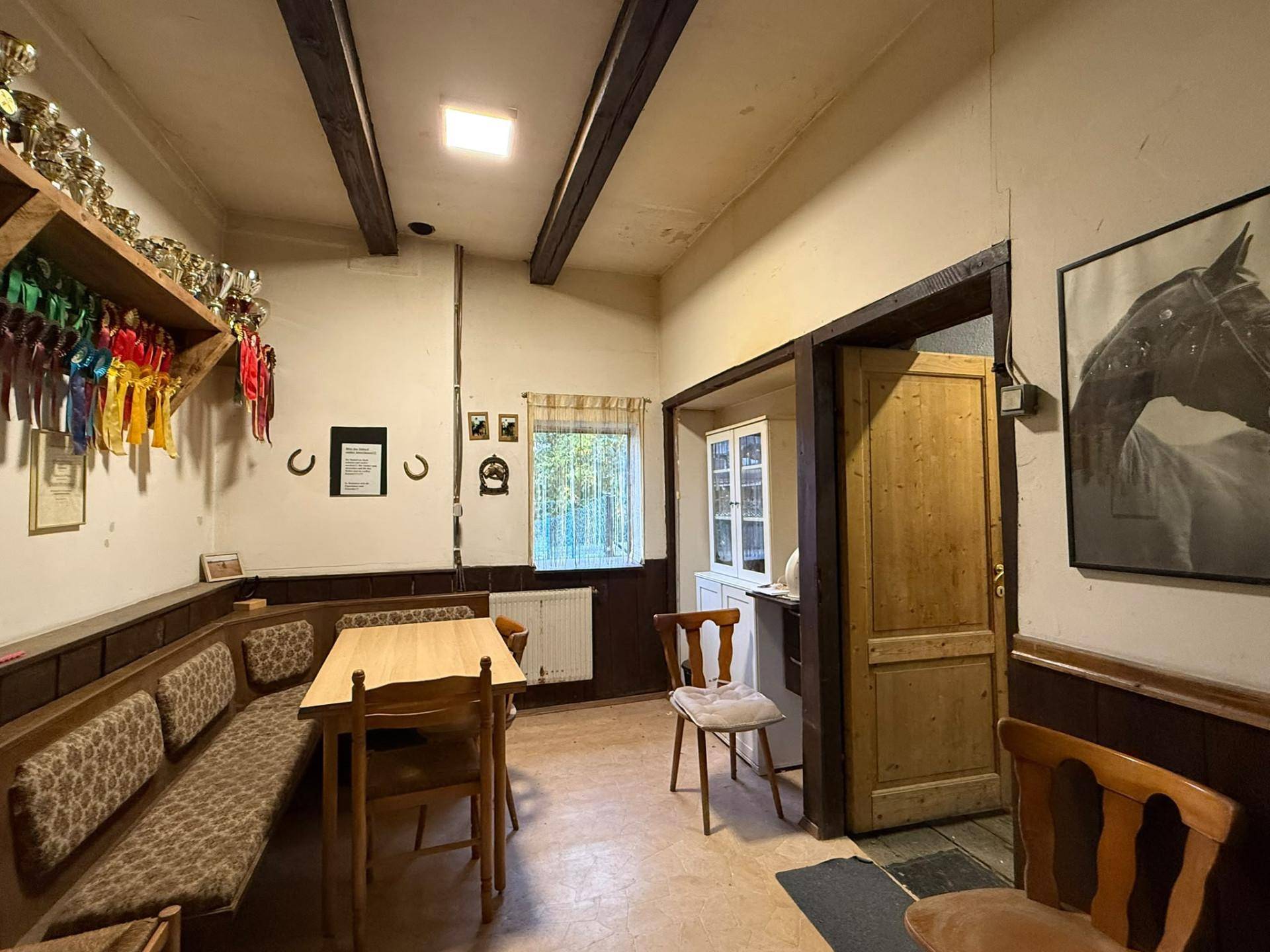 Gemütlicher Gemeinschaftsraum mit Holzbänken, Tischen und Auszeichnungen an der Wand, traditionell eingerichtet.