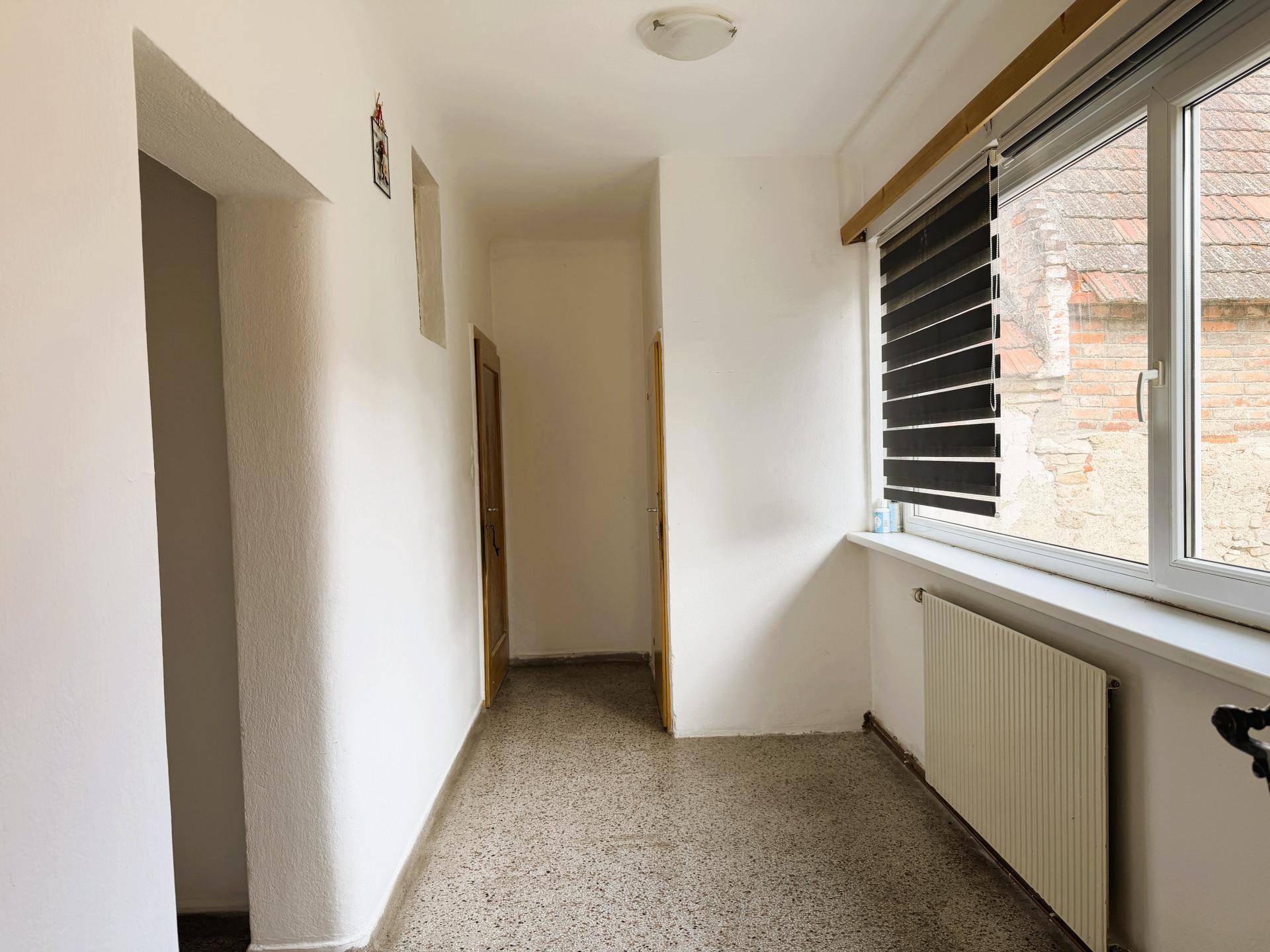 Heller Flur mit Fenster und Heizkörper, der den Zugang zu verschiedenen Zimmern ermöglicht.