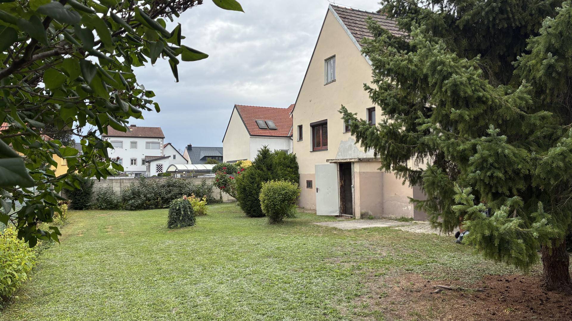 Weitläufiger Garten mit Rasenfläche und Blick auf die Rückseite des Hauses.