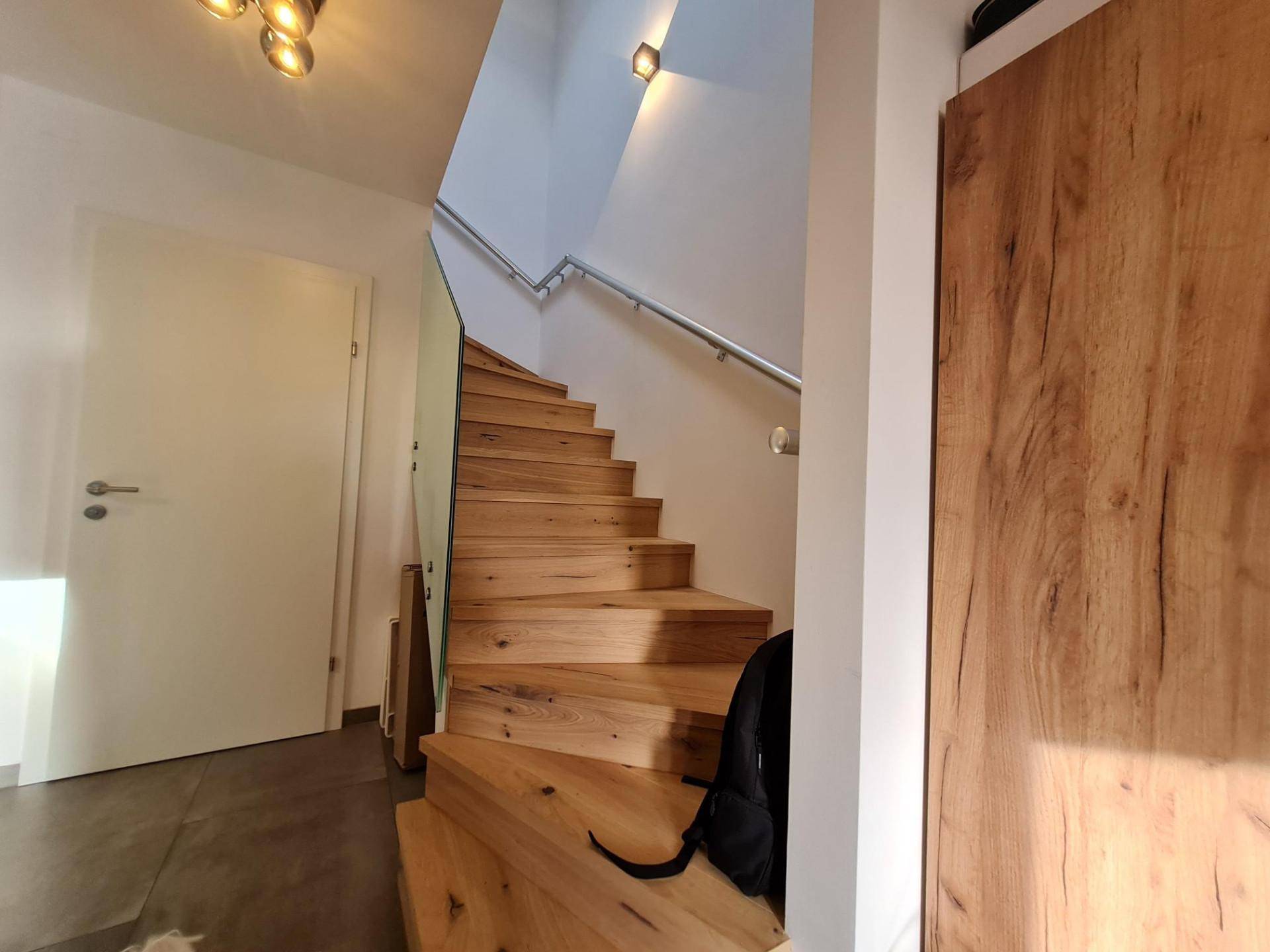 Elegante Holztreppe mit Glasgeländer, die in die oberen Stockwerke führt.