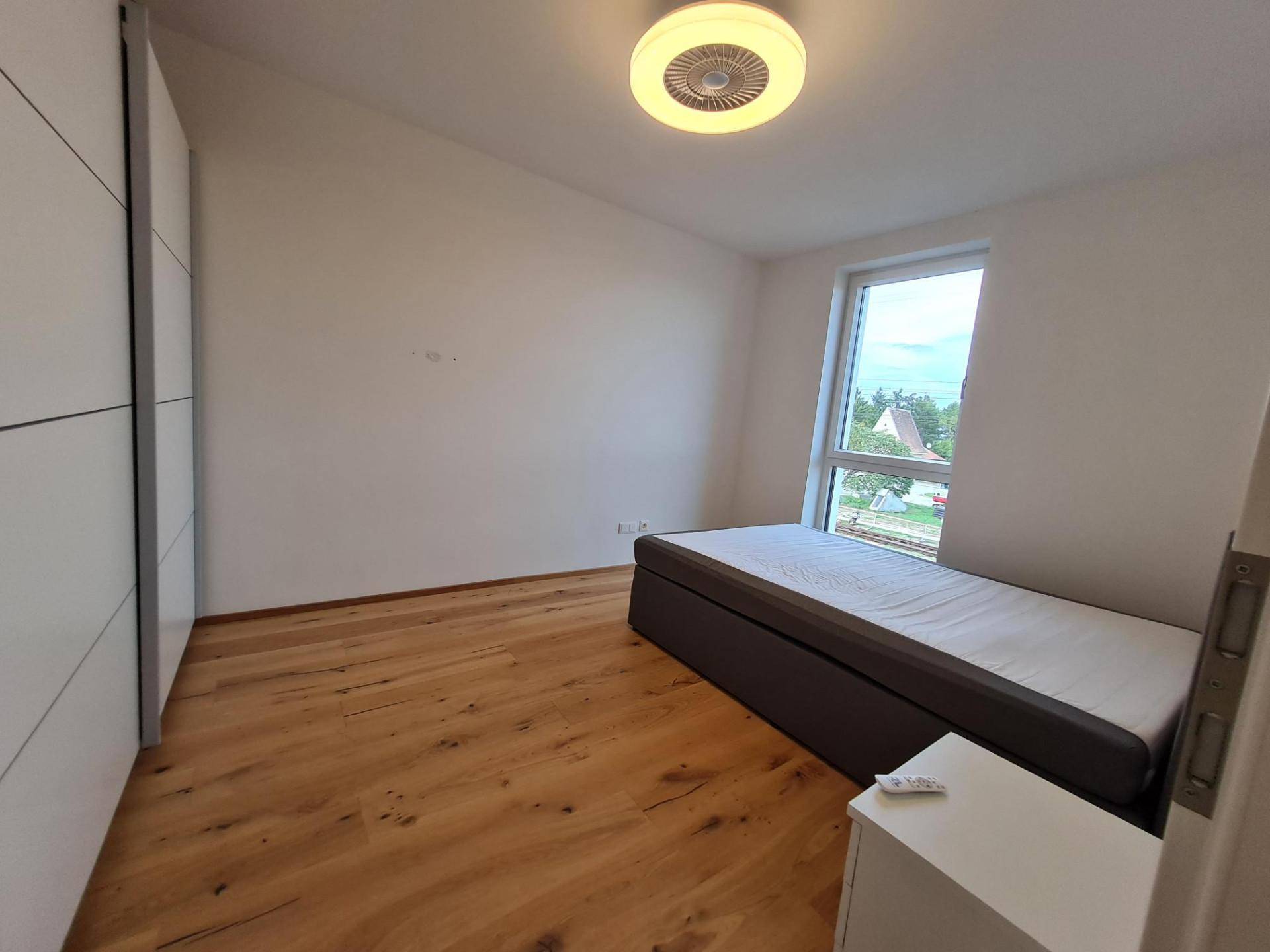 Helles Schlafzimmer mit Einzelbett, weißem Kleiderschrank und Holzboden.