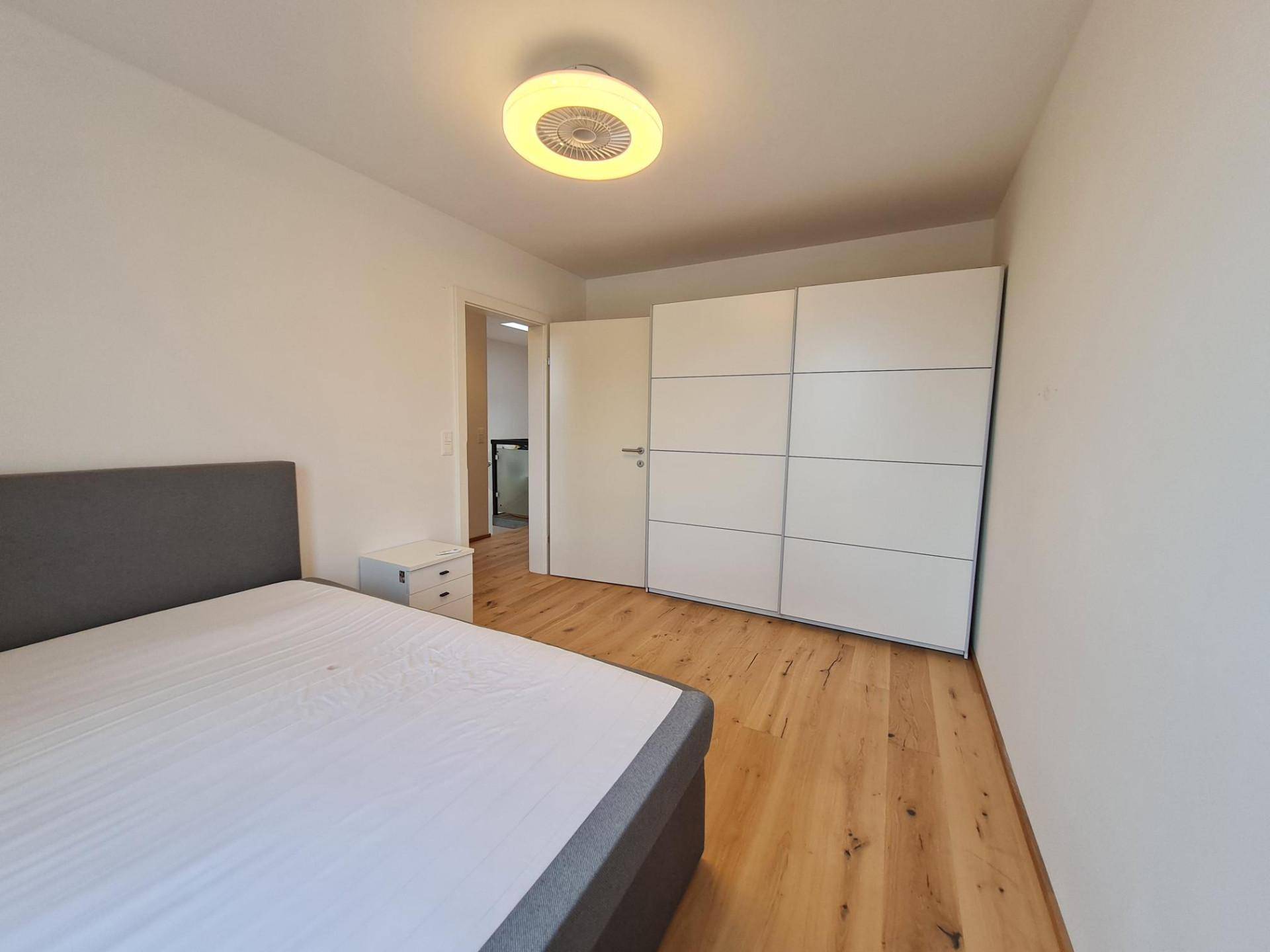 Geräumiges Schlafzimmer mit Doppelbett, großem weißen Kleiderschrank und Holzboden.