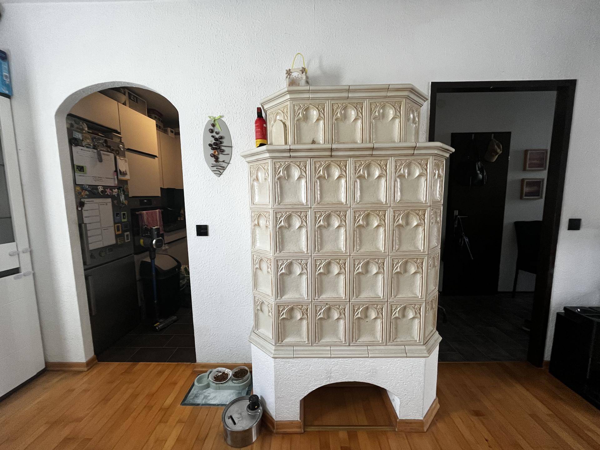 Traditioneller Kachelofen als Blickfang im Essbereich mit Holzboden und Durchgang zur Küche.