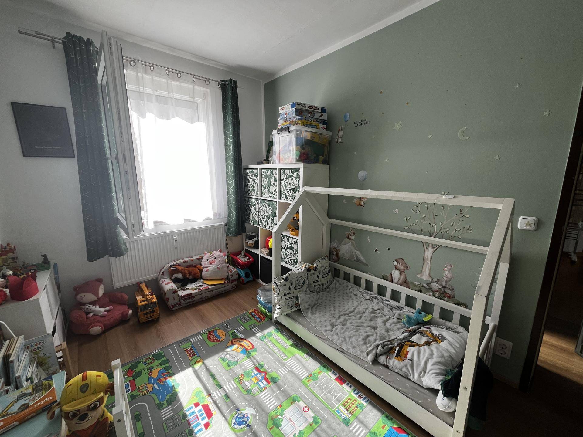 Helles Zimmer mit Spielbereich, Bett und Fenster, ideal für Kinder.