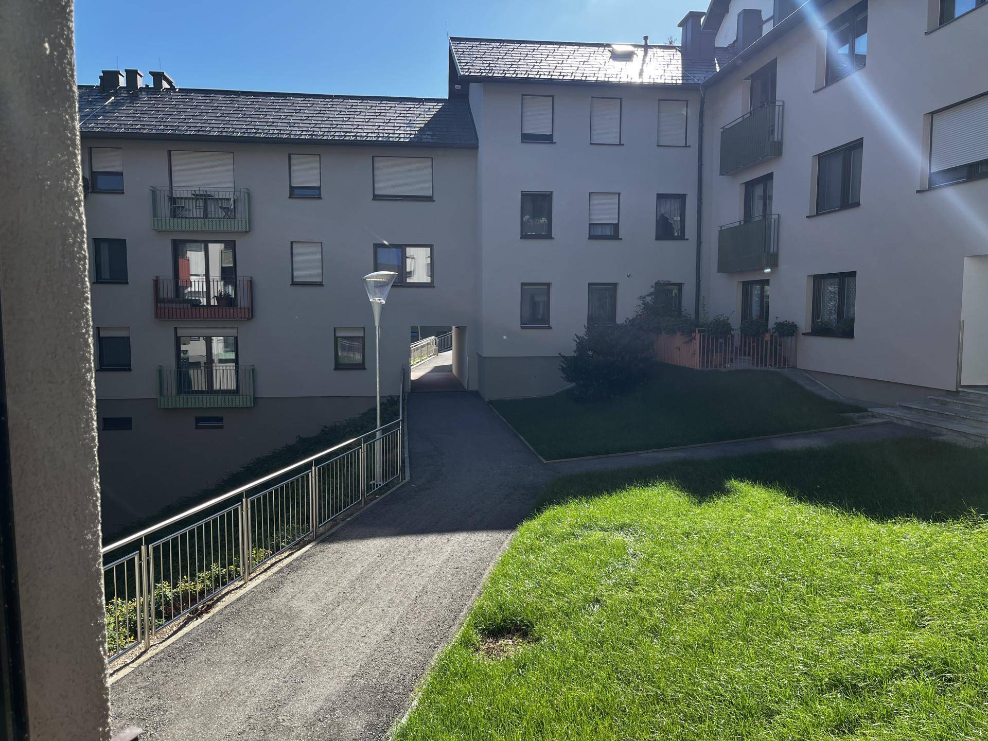 Außenansicht eines Wohngebäudes mit Grünflächen und einem Innenhof.