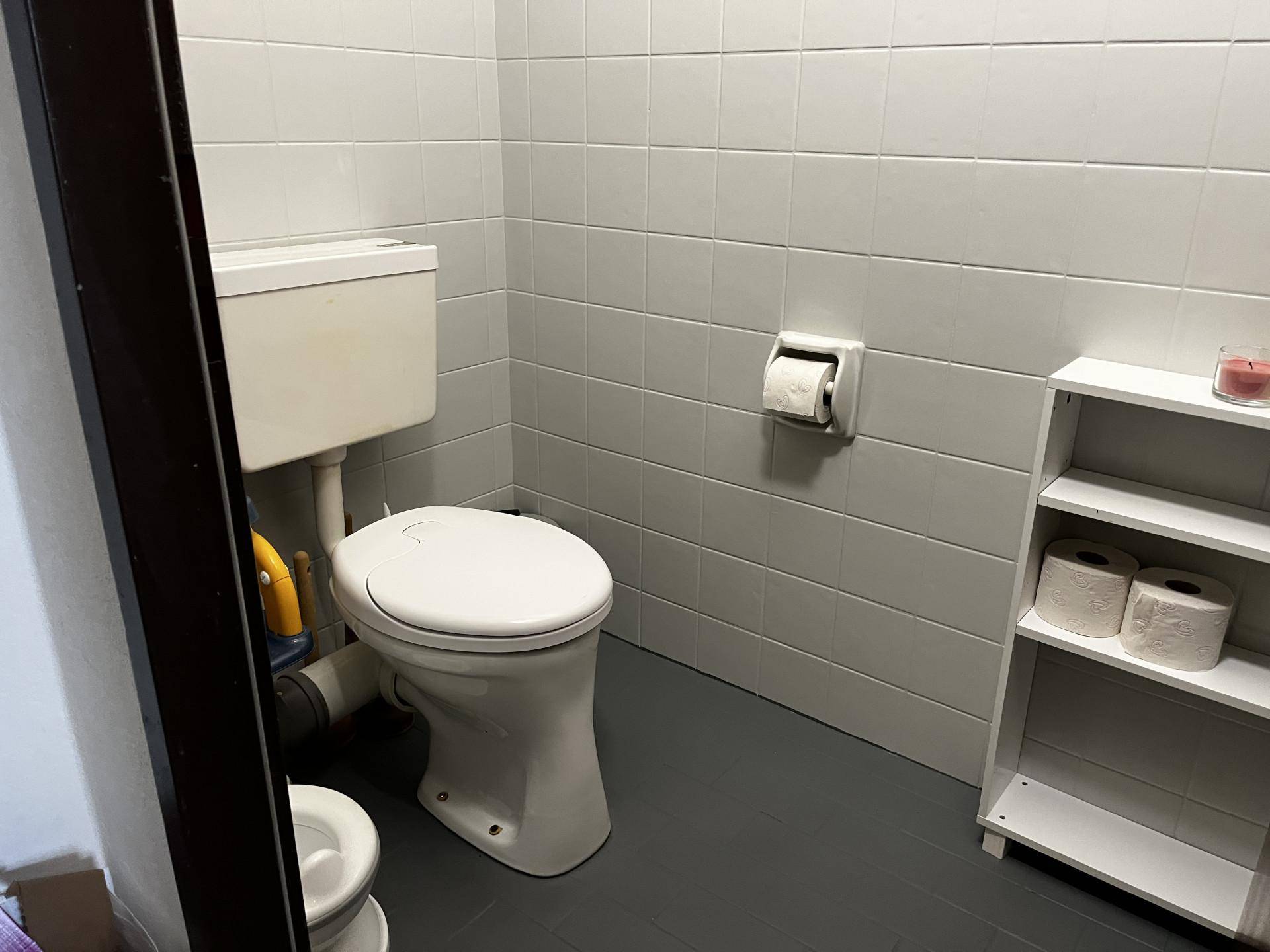 Kleines WC mit weißen Fliesen an Wänden und Boden.