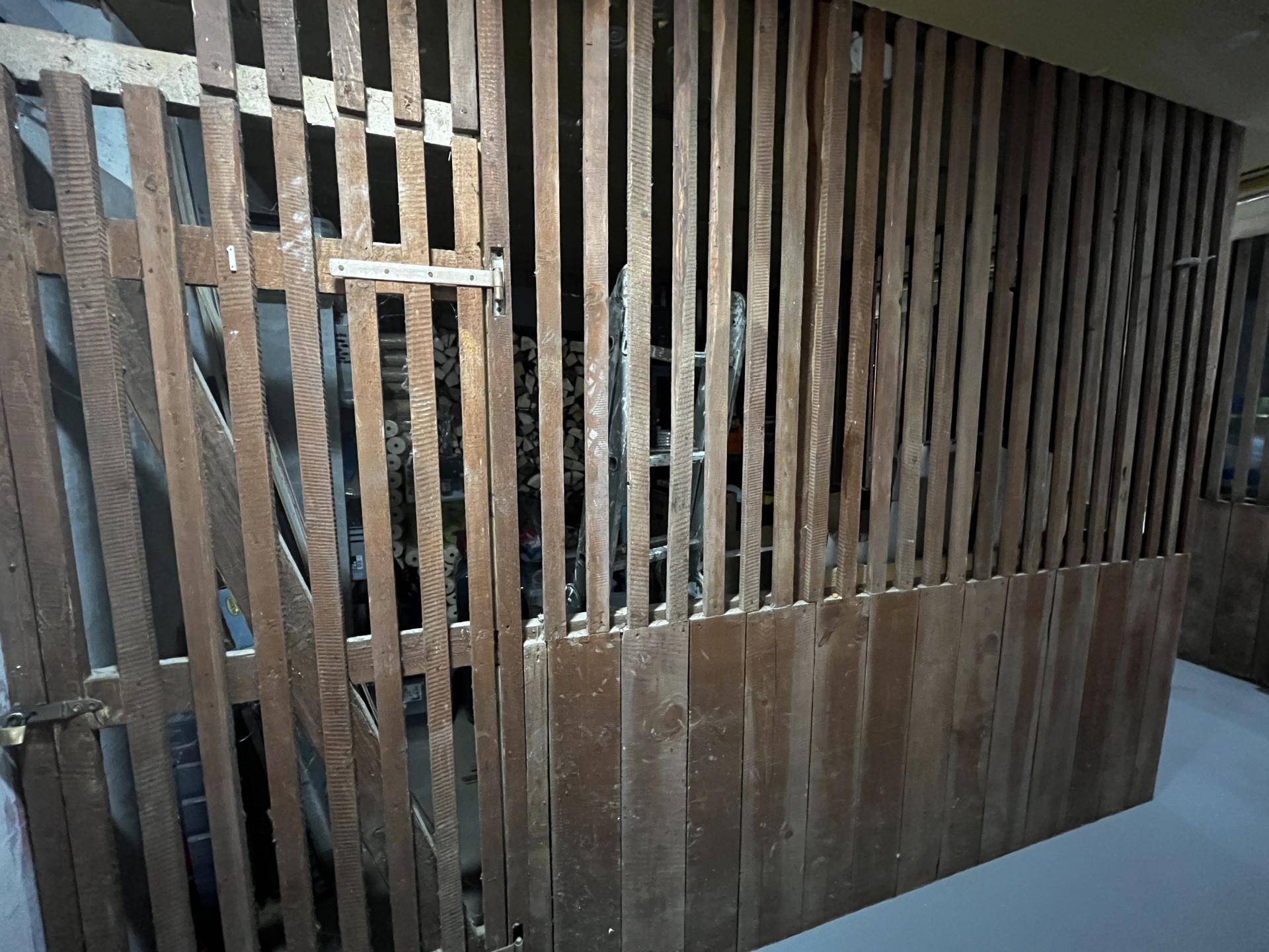 Abstellraum im Keller mit Holzlattenwänden und Stauraum.