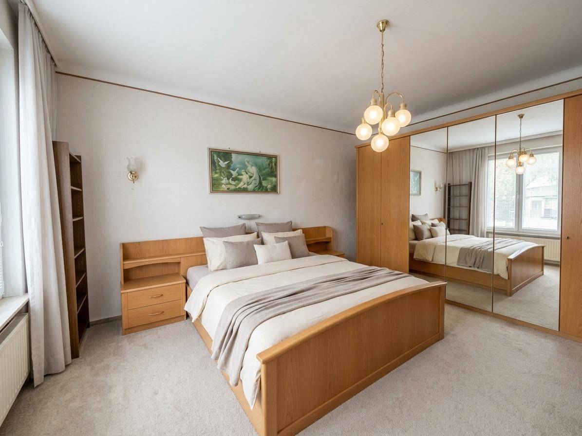 Gemütliches Schlafzimmer mit Doppelbett, Spiegelschrank und Teppichboden in hellem Holzton.