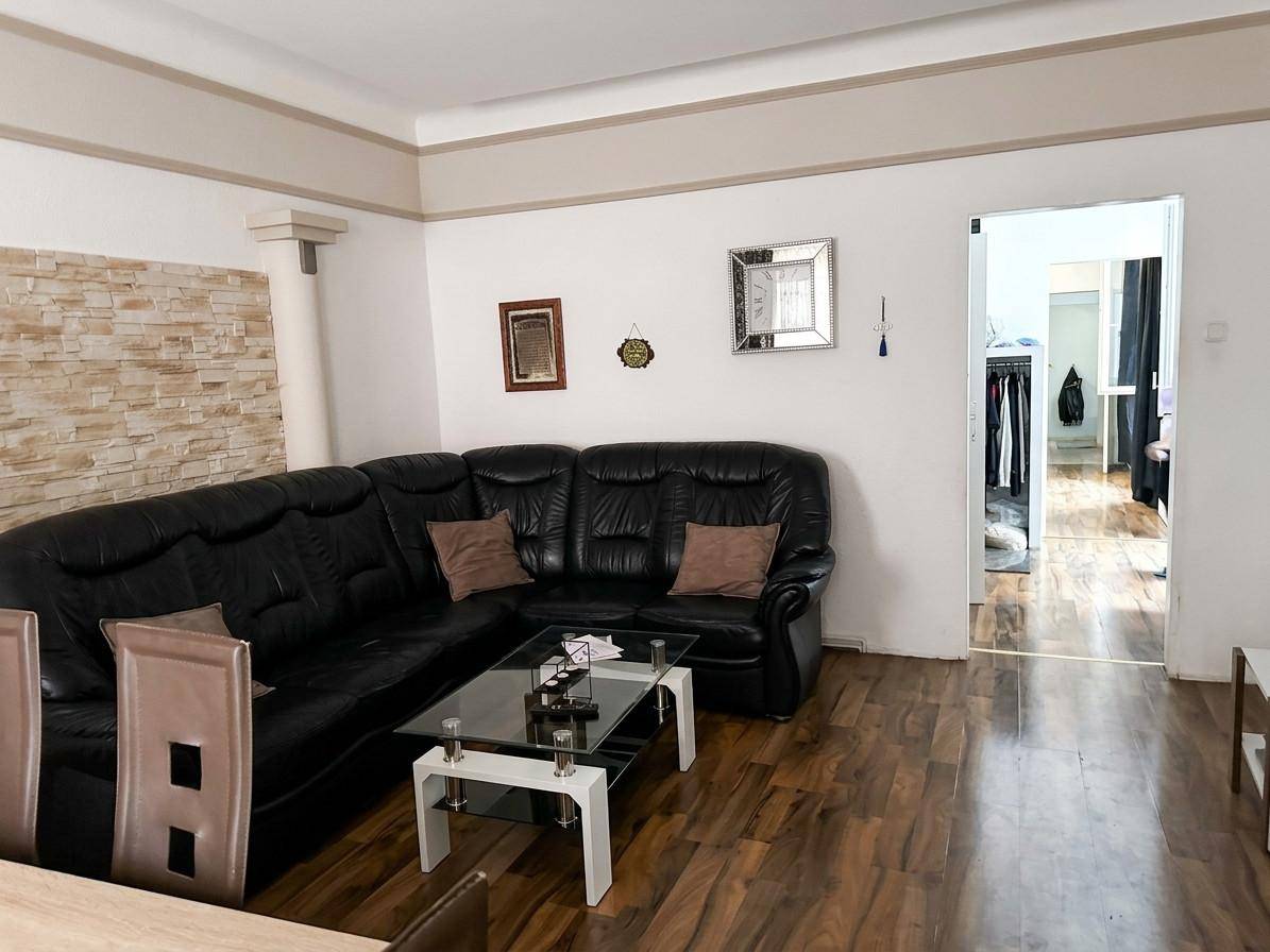 Wohnzimmer mit schwarzem Ledersofa, Couchtisch und einer dekorativen Steinwand.