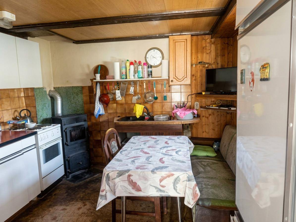 Rustikale Küche mit Holzvertäfelung, einem Esstisch mit Bank und einem traditionellen Ofen.