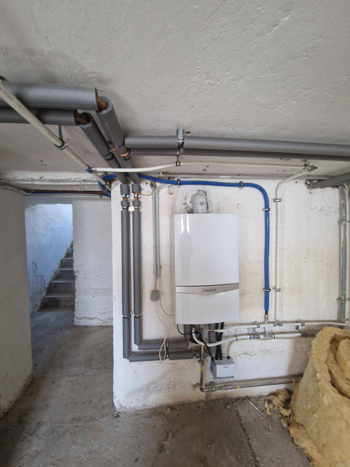 Kellerraum mit Heizungsanlage und sichtbaren Rohrleitungen, der als Technikraum dient.