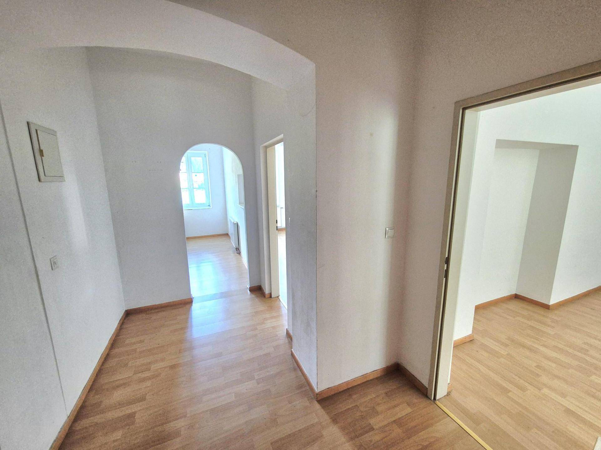 Heller Flur mit Laminatboden und Rundbogen, der zu weiteren Räumen führt.