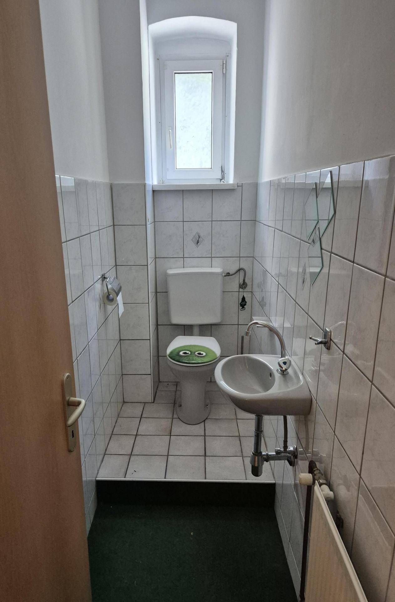Kleines WC mit Fliesenboden, Fenster und einem Waschbecken.