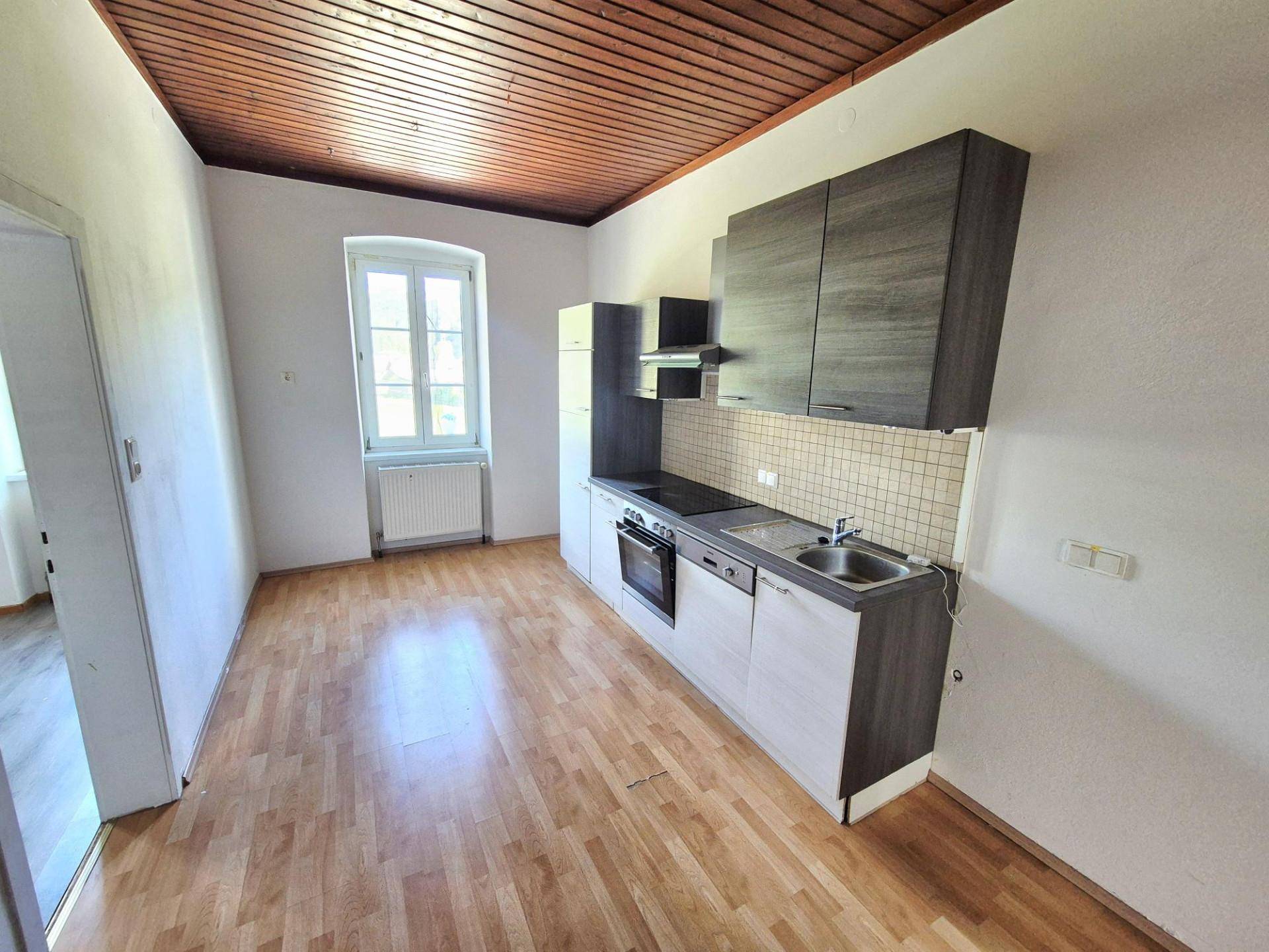 Geräumige Küche mit Holzbalkendecke, Laminatboden und moderner Einbauküche.