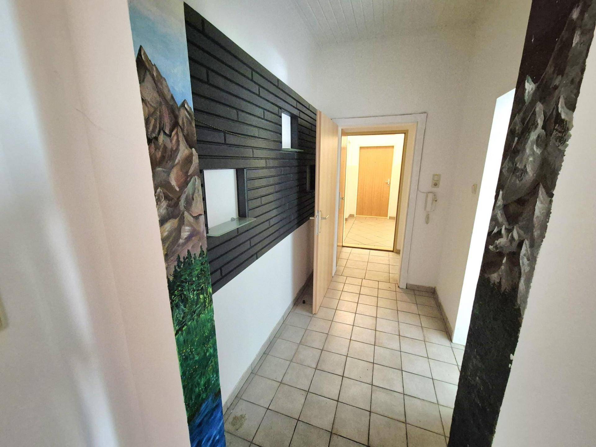 Flur mit Fliesenboden und dekorativer Wandgestaltung, die zu weiteren Räumen führt.