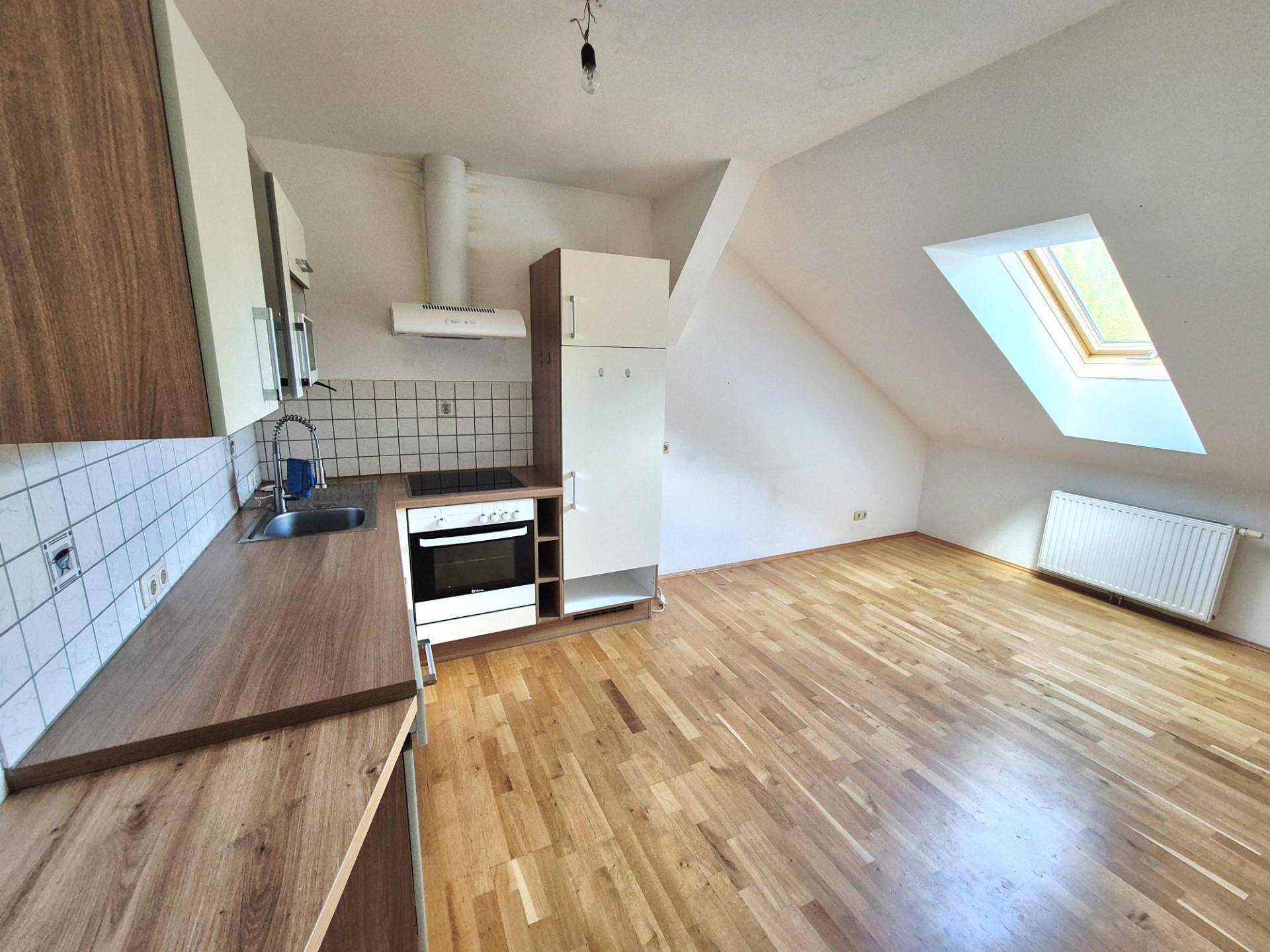 Dachgeschossküche mit Holzboden, Einbauküche und Dachfenster für viel Licht.
