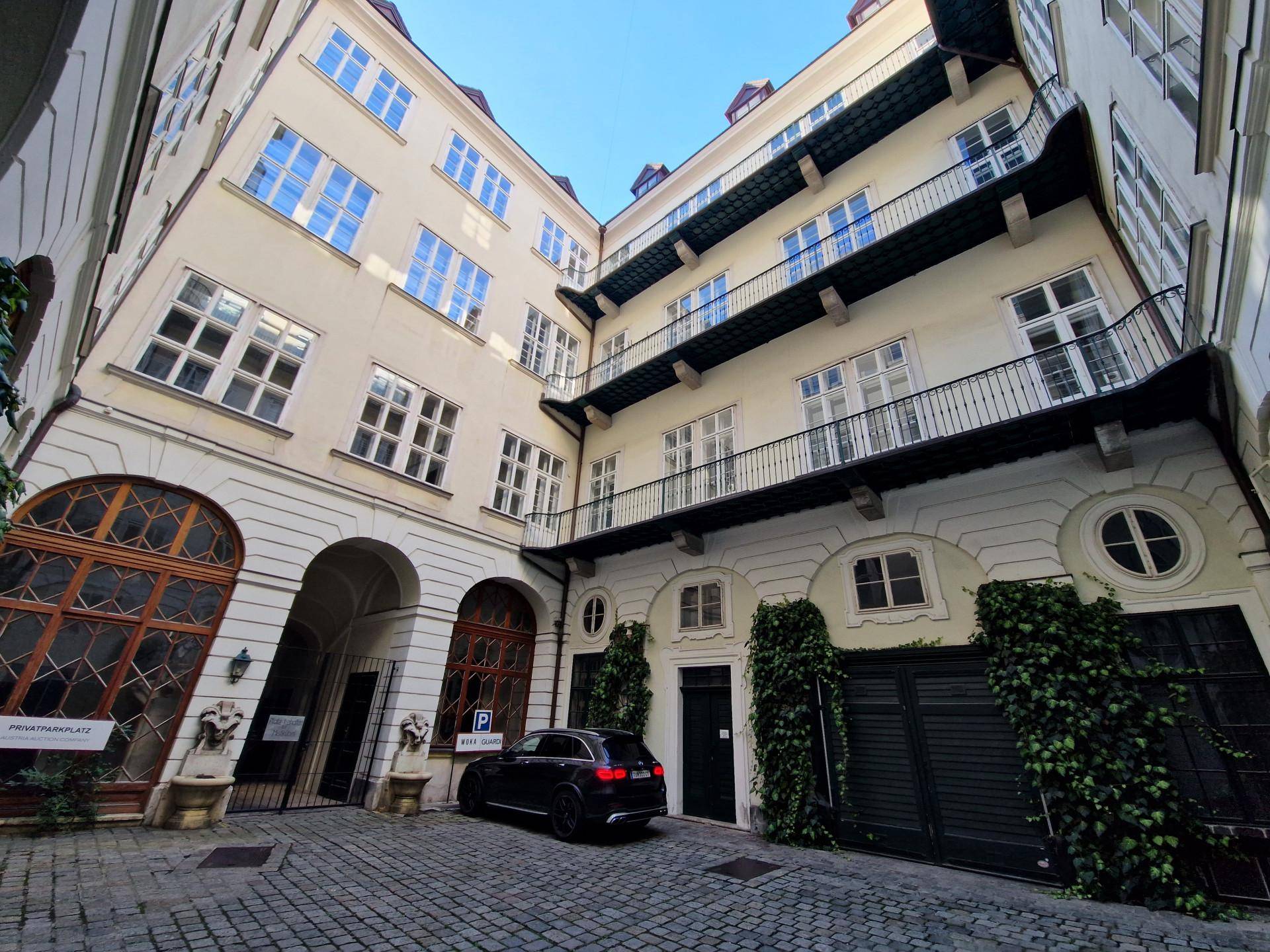 Historischer Innenhof mit Kopfsteinpflaster, Balkonen und einem geparkten Auto.