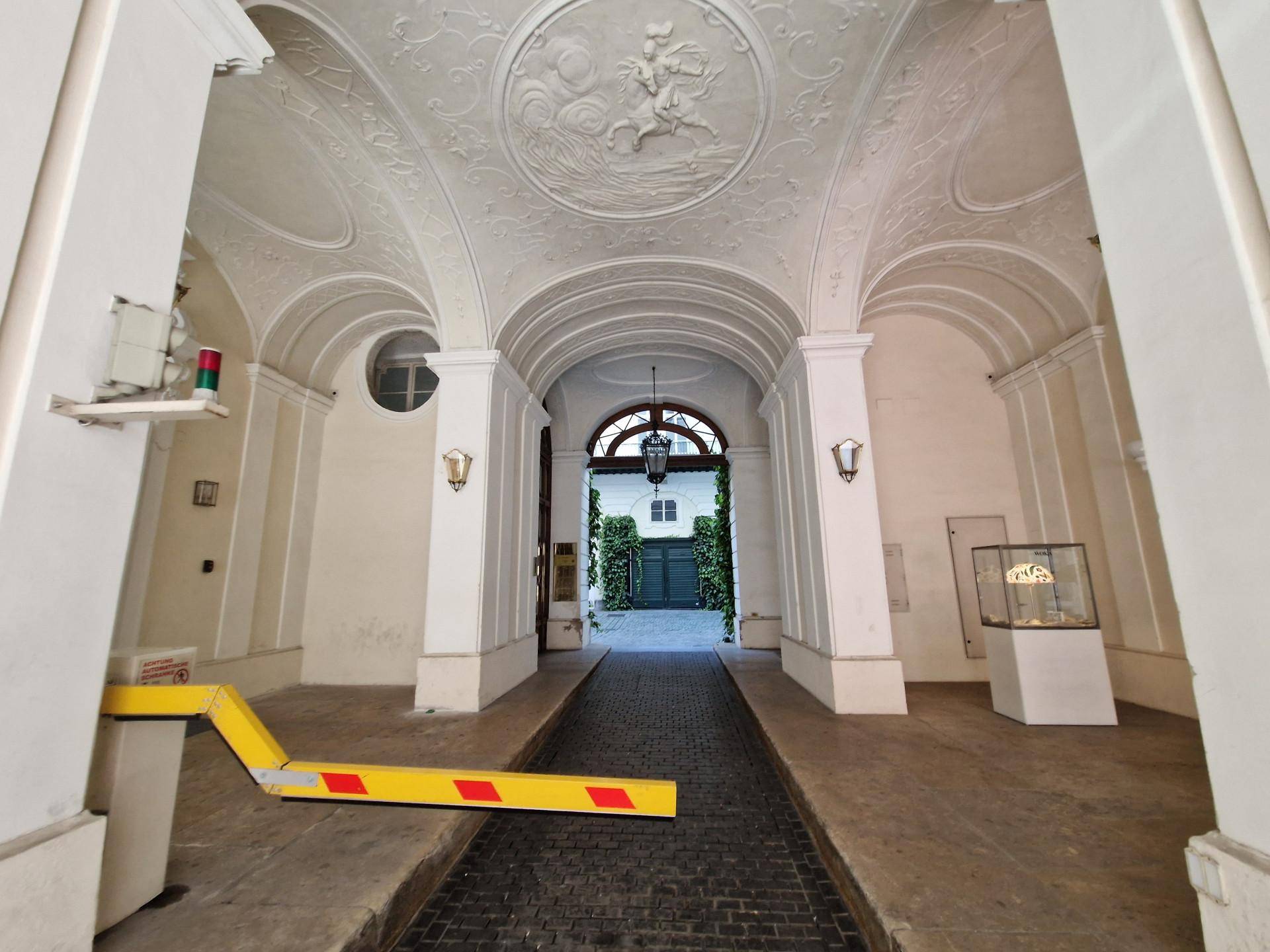 Gewölbter Durchgang mit Stuckverzierungen und einem Blick in einen weiteren Innenhof.