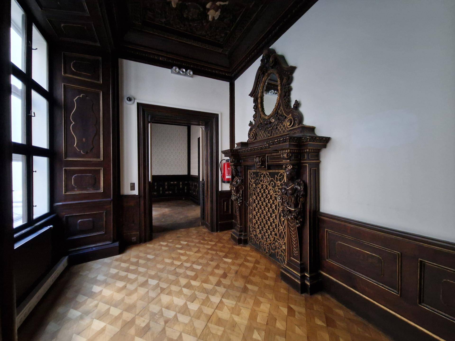 Ecke eines Raumes mit Holztäfelung, Kassettendecke und einem verzierten Kamin.